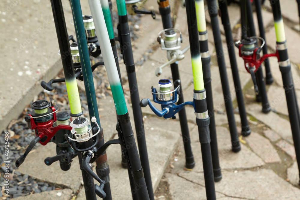 Rods with reels covered with drops of water stand on ground Rods with reels covered with drops of water stand on ground