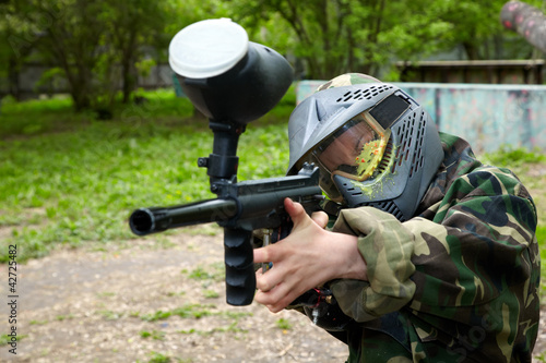 Paintball player in camouflage uniform and protective mask