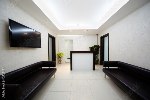 Hallway in beauty salon with two black leather divans