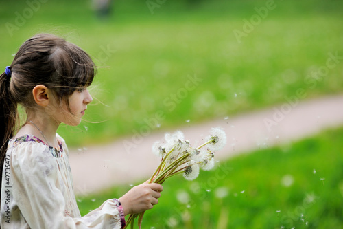 Child girl looking at dandelion seeds