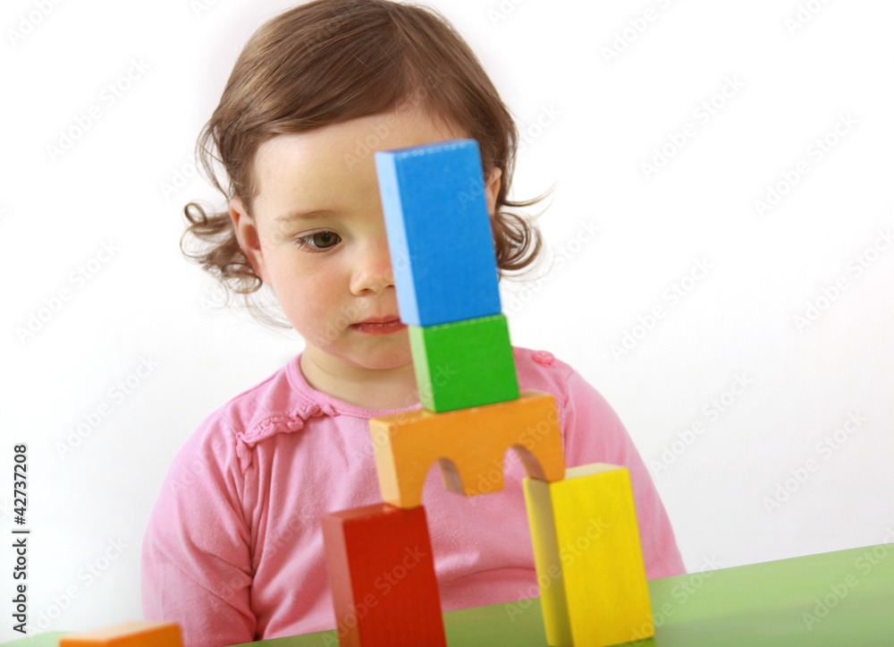 Ein Kleinkind baut einen Turm aus Bausteinen Ein Kleinkind baut einen Turm aus Bausteinen