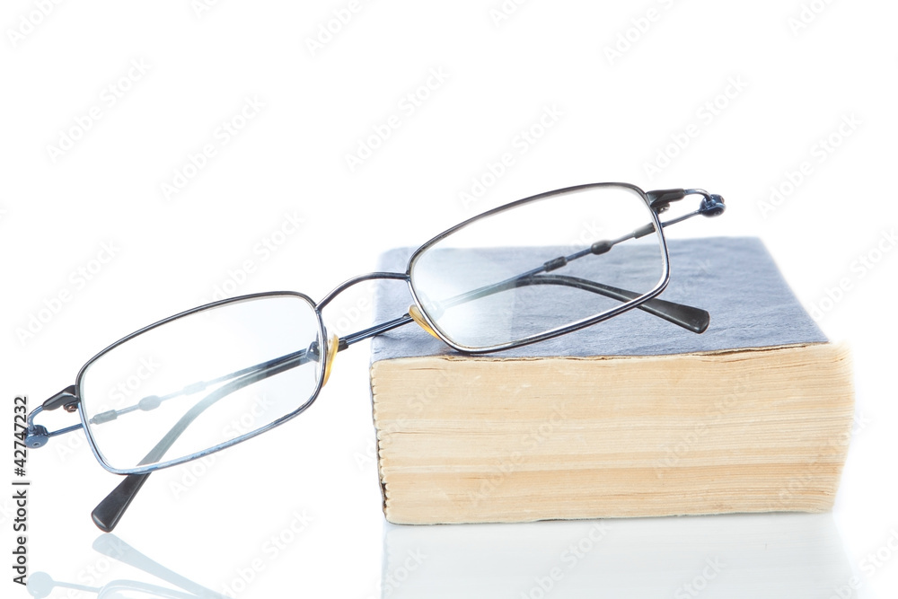 The book is a dictionary and glasses on a white background. The book is a dictionary and glasses on a white background.