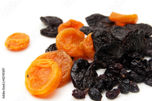 dried apricots, prunes and raisins on a white background