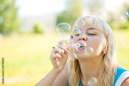  .Woman blowing bubbles in park