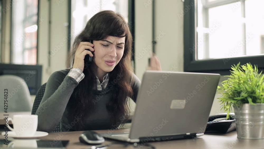 Angry businesswoman with cellphone and laptop Angry businesswoman with cellphone and laptop