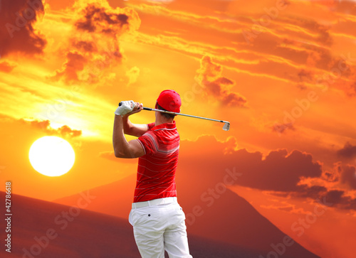 Man playing golf against sunset