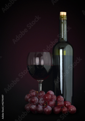 red wine in glass with grapes and bottle