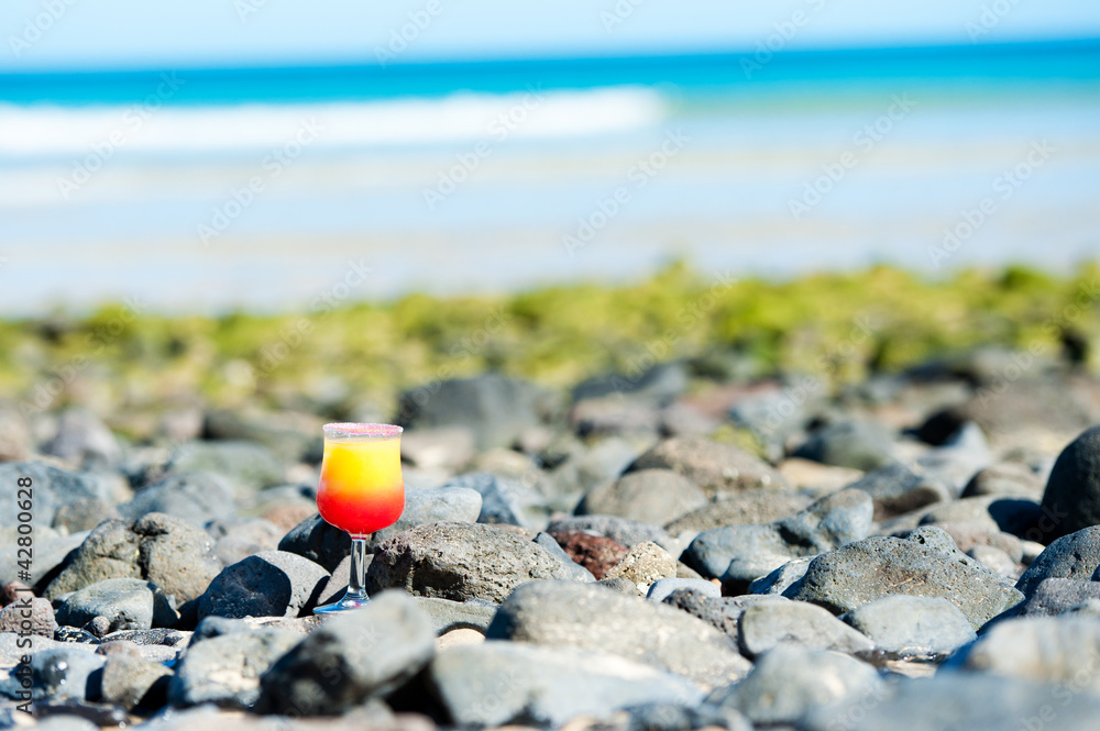 a glass with drink on the beach by the sea a glass with drink on the beach by the sea