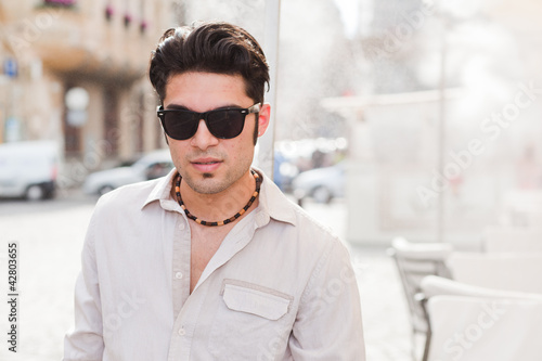 attractive man wearing sunglasses looking cool on the street