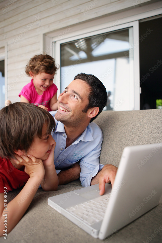 Father and children laughing at with a laptop Father and children laughing at with a laptop