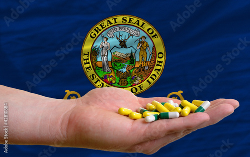 holding pills in hand in front of idaho us state flag photo