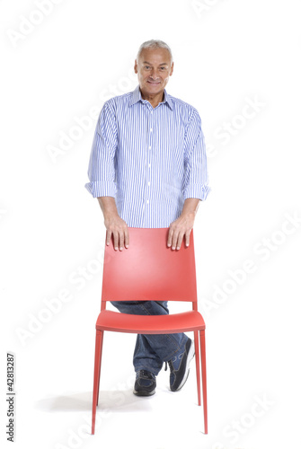 Señor de pie sujetando una silla roja.