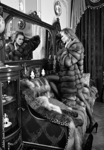 woman in fur coat at the mirror in Luxurious classical interio