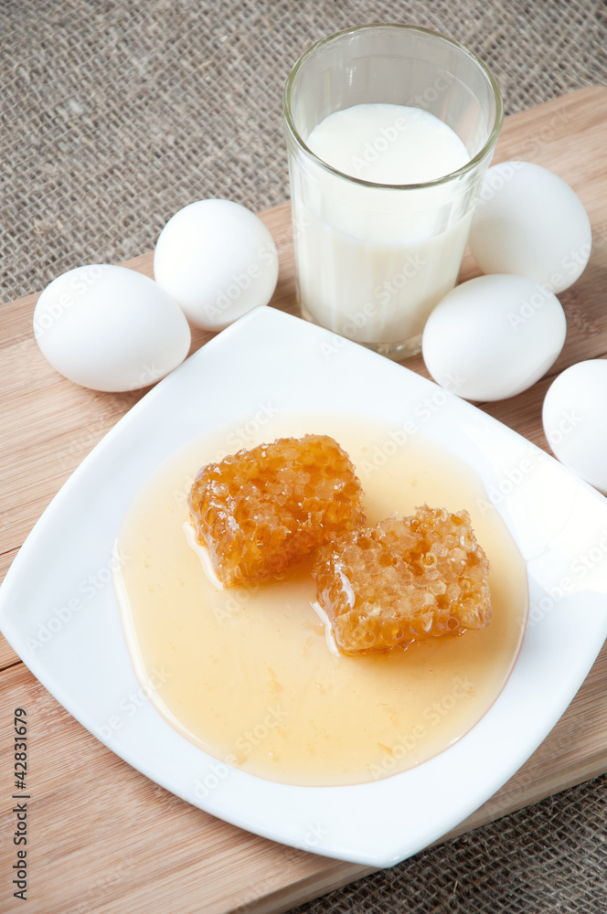 Glass plate with fresh honey, chicken eggs and milk Glass plate with fresh honey, chicken eggs and milk
