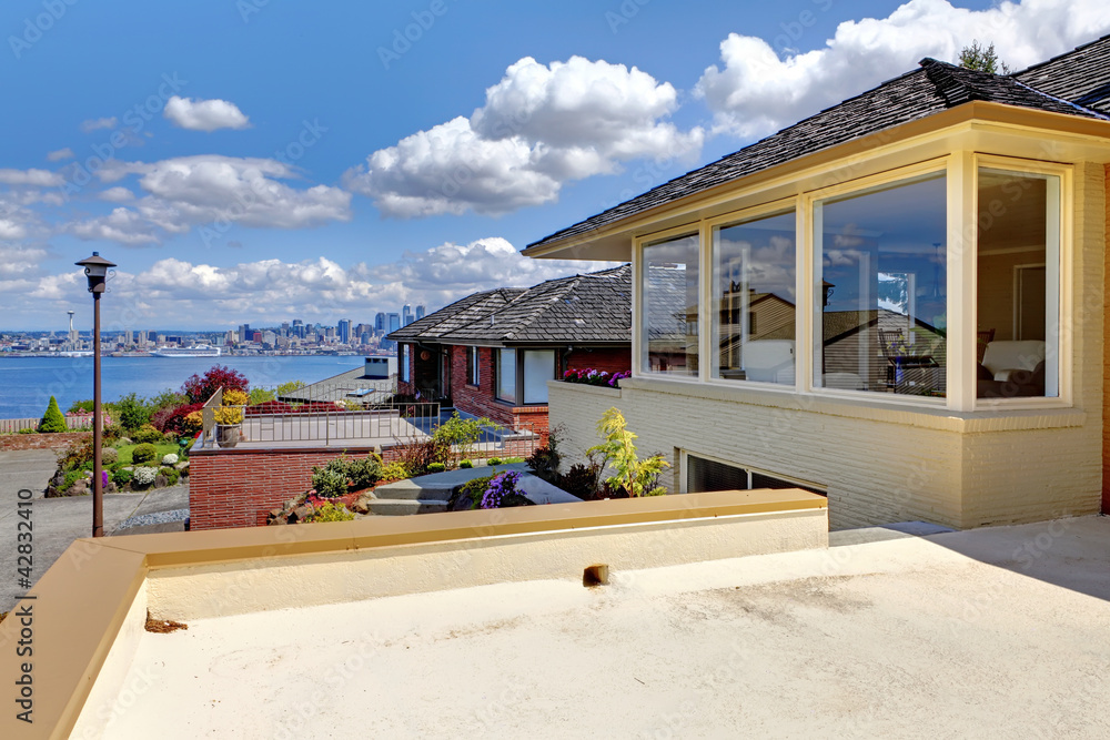Modern house with patio and view of Seattle and water.
