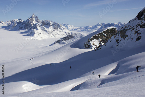 Montée à ski sur pente crevassée et paysage glaciaire infini.