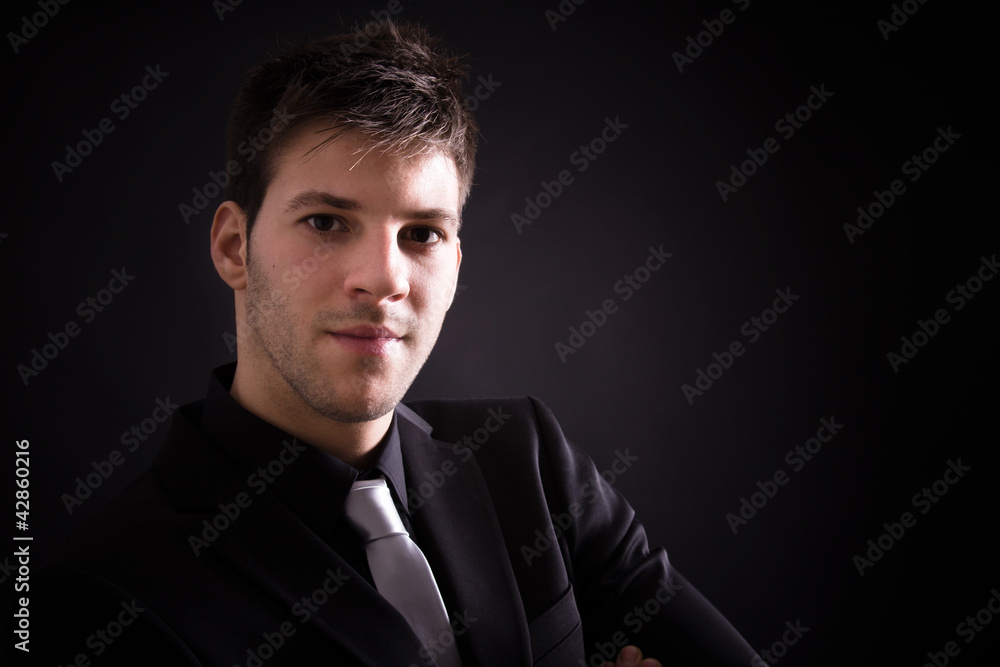 Portrait of handsome stylish man in elegant black suit against b Portrait of handsome stylish man in elegant black suit against b