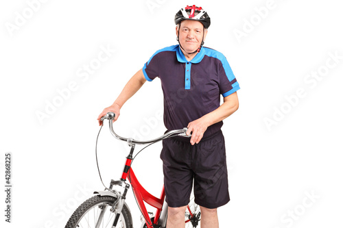 A senior bicyclist posing next to a bicycle