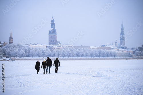 People crossing a frozen river in  Riga, Latvia