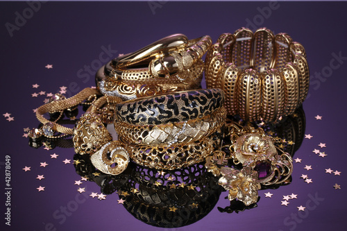 Beautiful golden jewelry on purple background