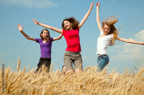 Teen girl jumping at a wheat field