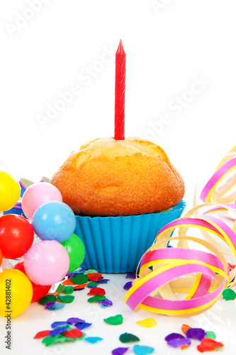 Birthday cupcake with candle, party streamers and colorful confe