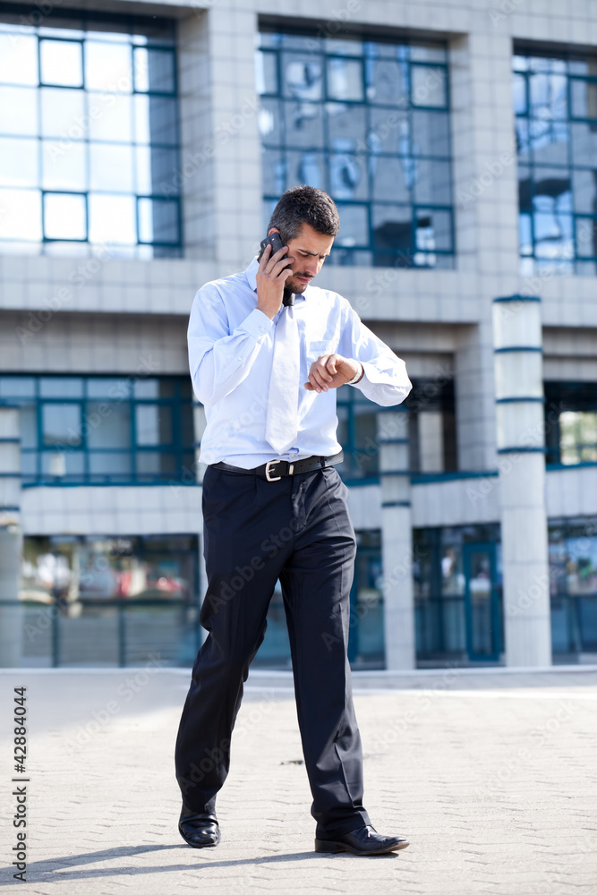 Man on phone and checking his watch Man on phone and checking his watch