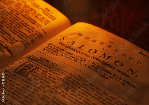 Very old bible by candle light photo