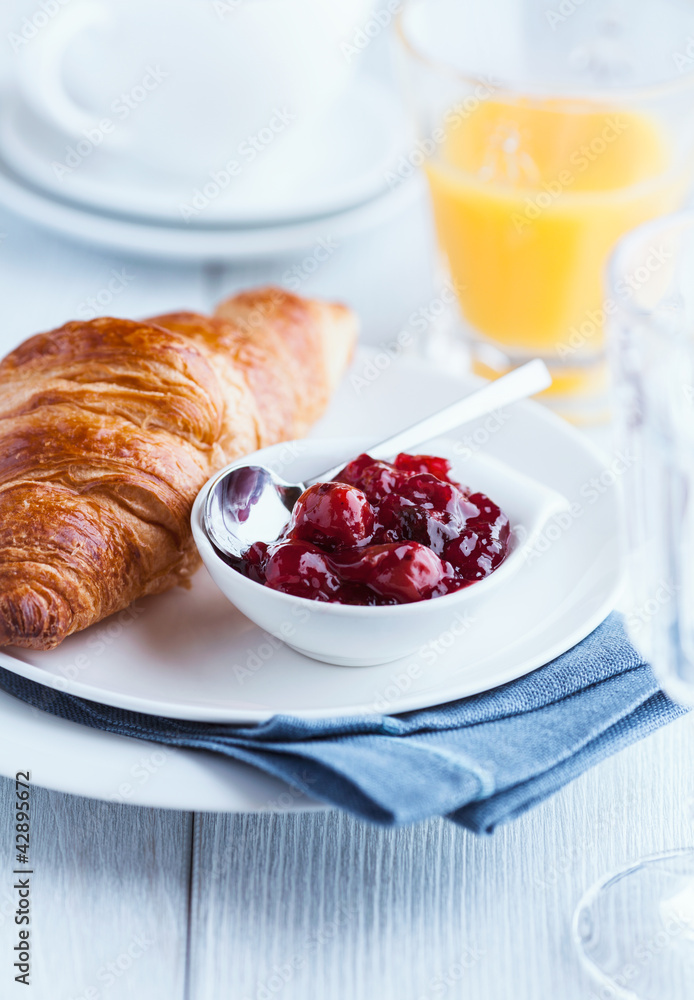 Croissant with sour cherry jam on a plate Croissant with sour cherry jam on a plate