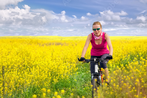 young woman cycling in canola field