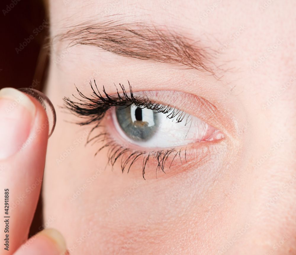 Fototapeta premium Close up of inserting a contact lens in female eye