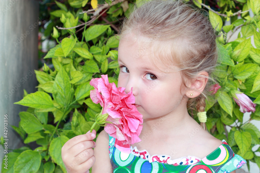 Bambina in giardino che odora un fiore Bambina in giardino che odora un fiore