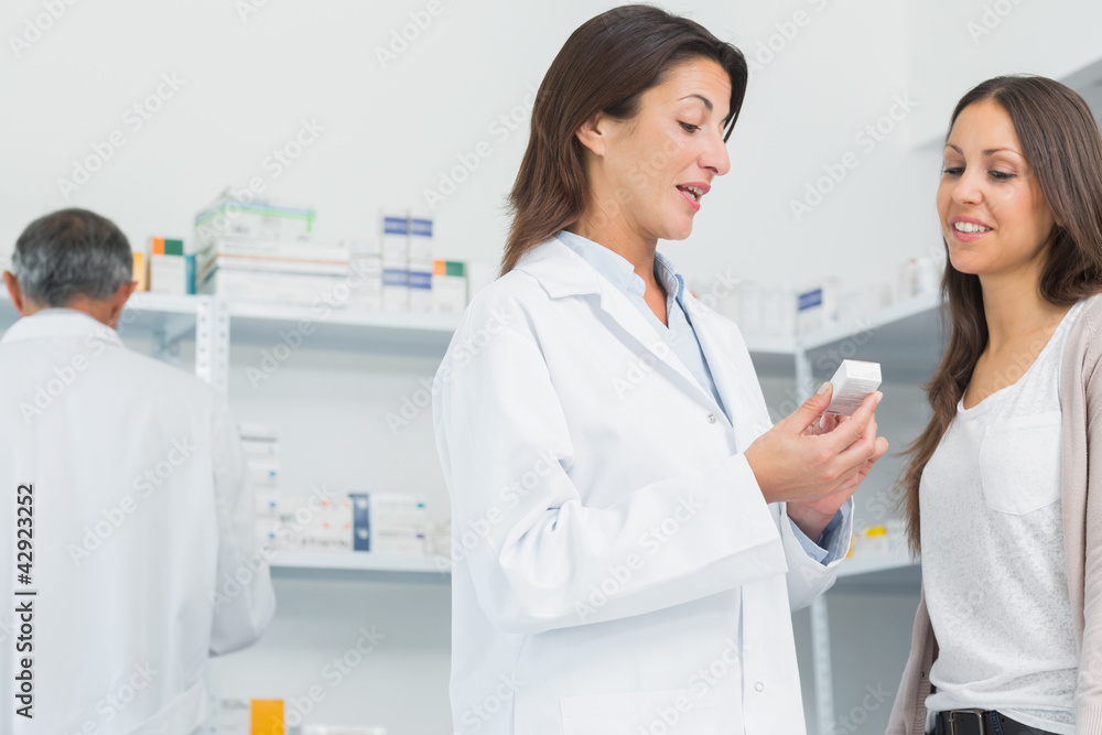 Pharmacist talking to a customer while holding pills Pharmacist talking to a customer while holding pills