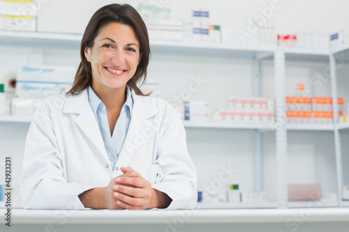 Smiling woman pharmacist behind a counter joining her hands photo