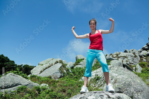 Fitness girl on top of rocks with arms wide open