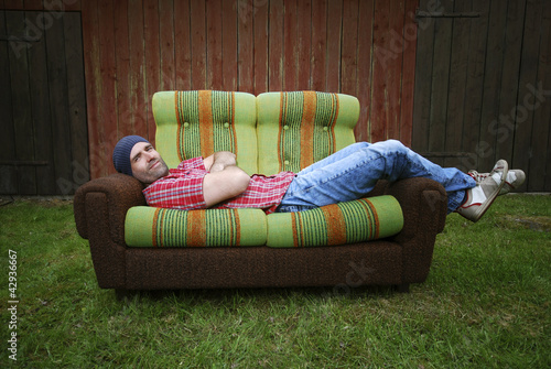 Lächelnder Mann liegt auf einer Couch