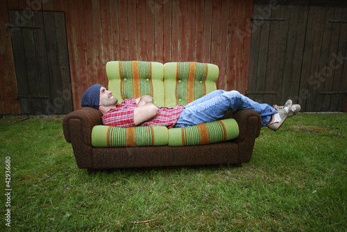 Lächelnder Mann liegt auf einer Couch photo