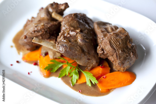 Foto Civet de lièvre en sauce et carottes dans un plat blanc