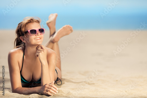 Bright photo of a beautiful model relaxing on a beach. Room for