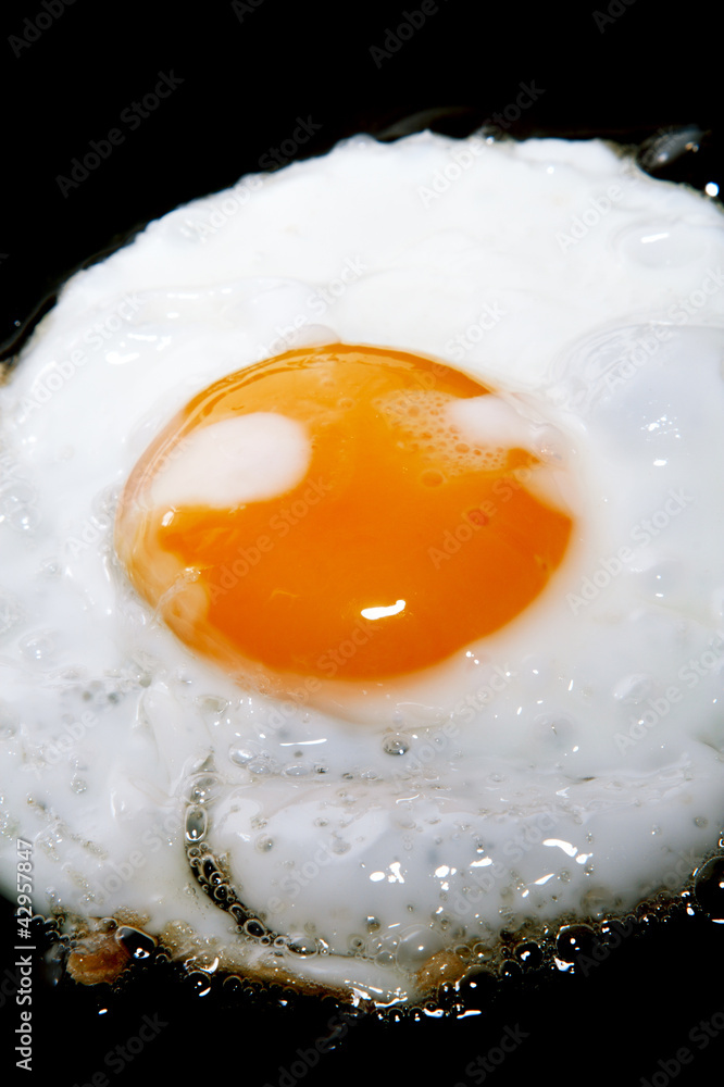 cooking frying egg with yolk on black pan cooking frying egg with yolk on black pan