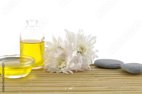 Chrysanthemum with massage oil and stones on bamboo mat