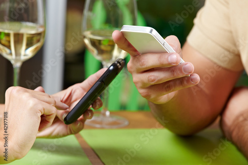 Paar mit Smartphones im Restaurant photo