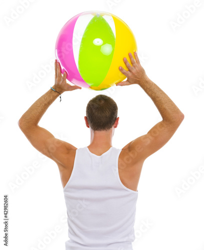 Man throwing beach ball. Rear view