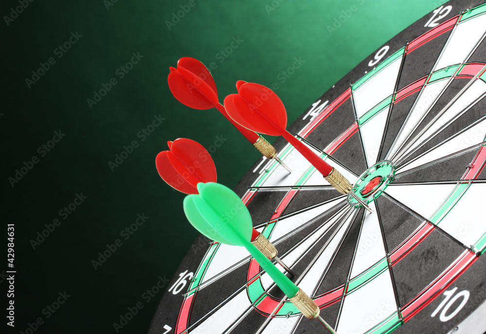 dart board with darts on green background dart board with darts on green background