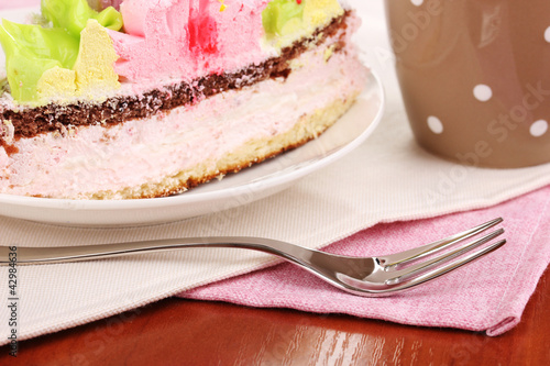 Creamy cake on saucer on table close-up