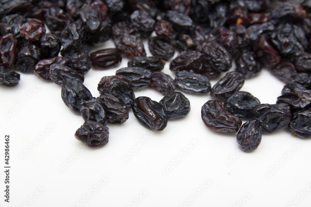 black raisins on a white background black raisins on a white background