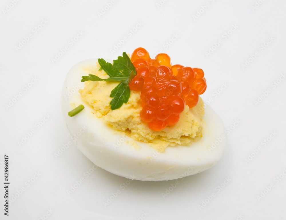 Egg with red caviar and parsley on a white background Egg with red caviar and parsley on a white background