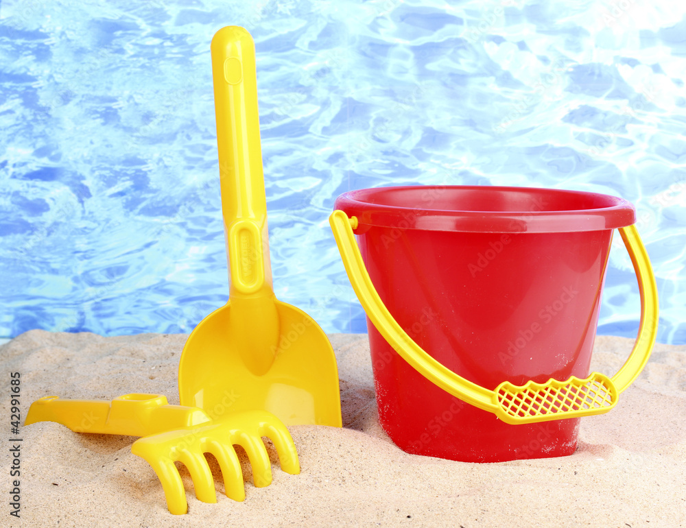 Children's beach toys on sand on water background Children's beach toys on sand on water background