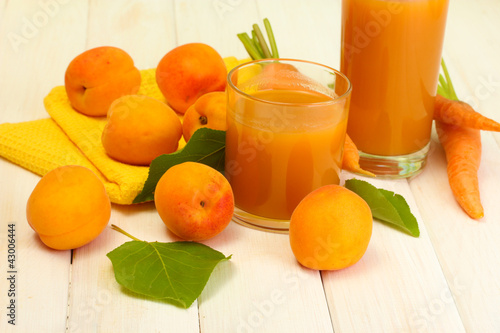 glasses of carrot and apricot juice on white wooden table