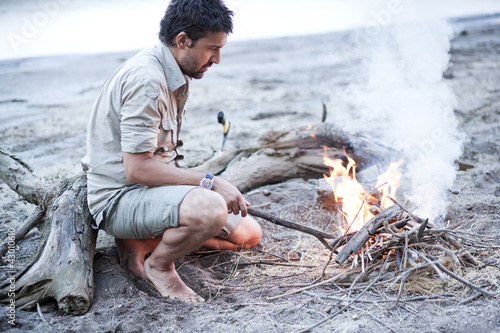 man standing by the fire on the river beach - series